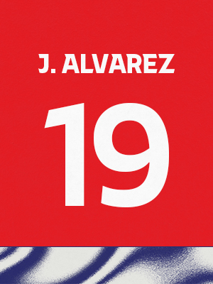 Dorsal de color rojo con el nombre 'J. Alvarez' y el número 19 en blanco, sobre un borde inferior con patrón ondulado azul y blanco.