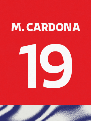 Dorsal de color rojo con el nombre 'M.Cardona' y el número 19 en blanco, sobre un borde inferior con patrón ondulado azul y blanco.