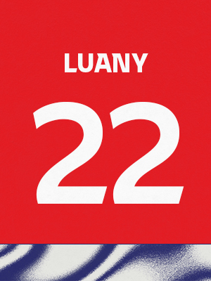 Dorsal de color rojo con el nombre 'Luany' y el número 22 en blanco, sobre un borde inferior con patrón ondulado azul y blanco.
