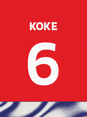 Dorsal de color rojo con el nombre 'Koke' y el número 6 en blanco, sobre un borde inferior con patrón ondulado azul y blanco.